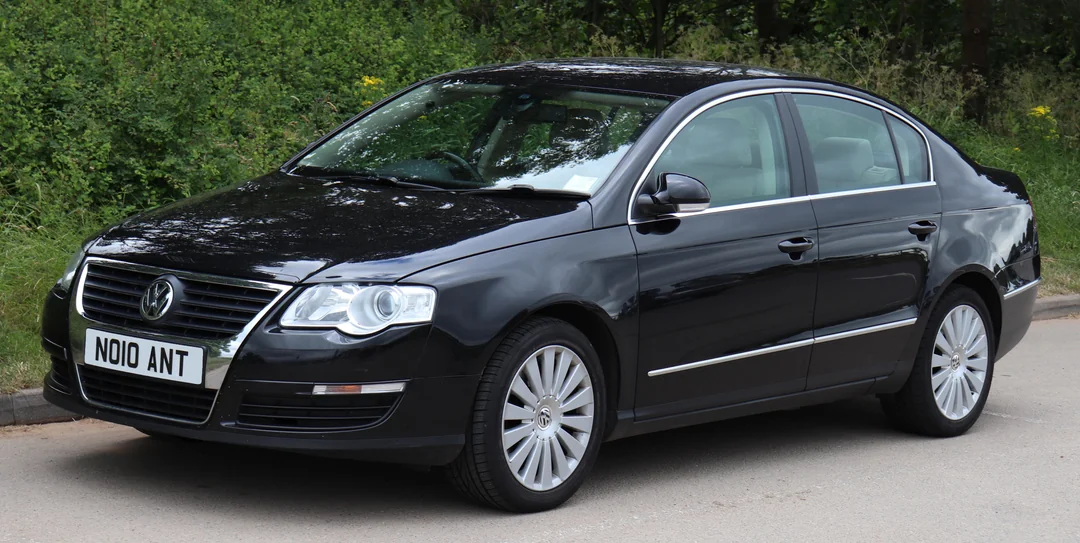A black Volkswagen sedan is parked on a road near greenery. The car has silver trim, alloy wheels, and a “N010 ANT” license plate.