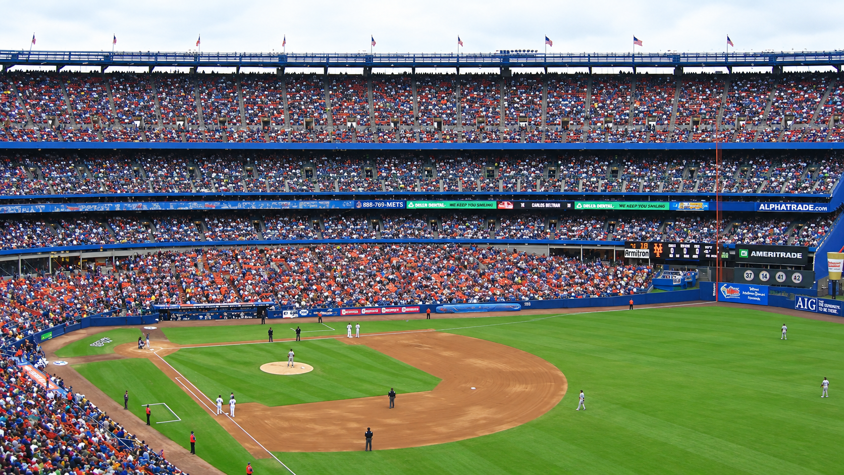 A crowded baseball stadium with a game in progress, players on the field, and spectators filling the stands on a bright day.