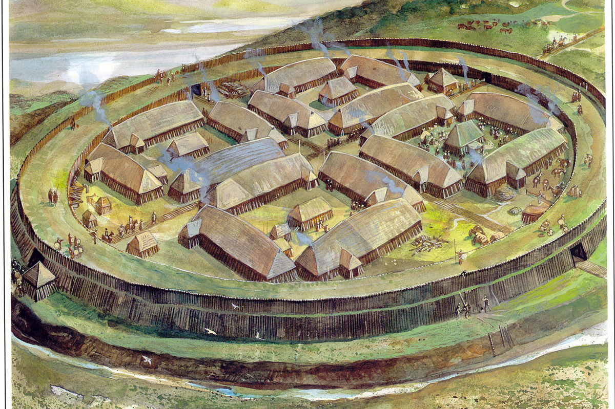 Illustration of a circular Viking settlement with wooden buildings and smoke rising from rooftops, surrounded by a tall wooden palisade and grassy landscape. People and animals move about inside the fort.