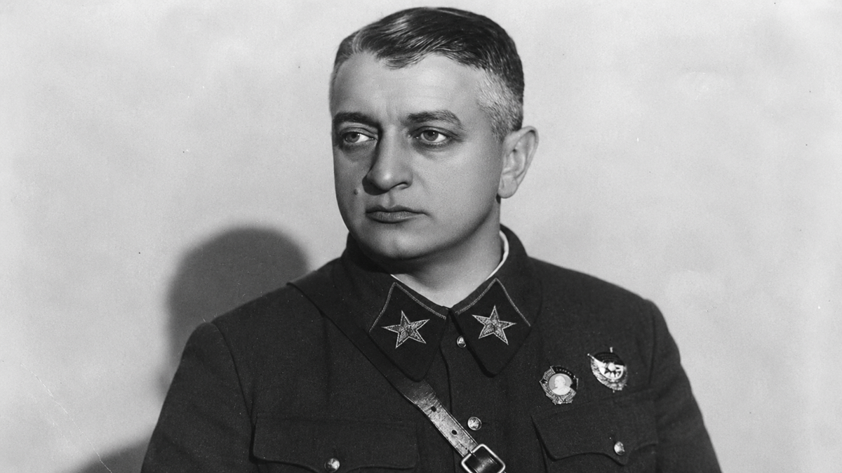 Black and white portrait of a man in a military uniform with two stars on his collar, a strap across his chest, and medals on his jacket, looking slightly to the side against a plain background.