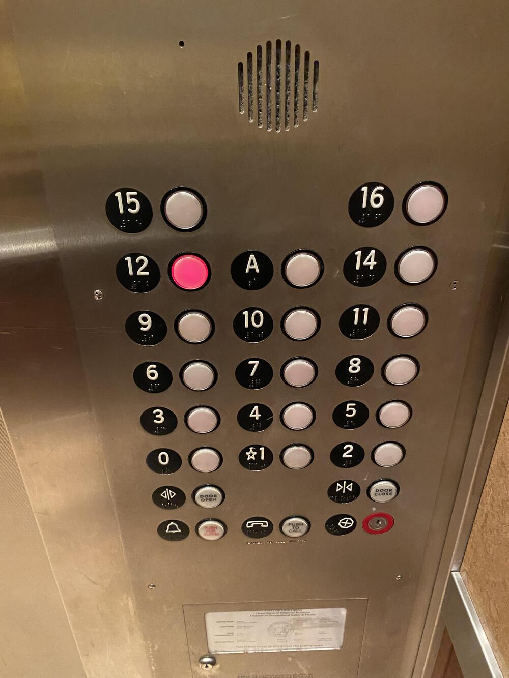 Elevator control panel with round buttons for floors 1 to 16, a red-lit button for floor 2, open/close door controls, emergency button, and a speaker at the top.