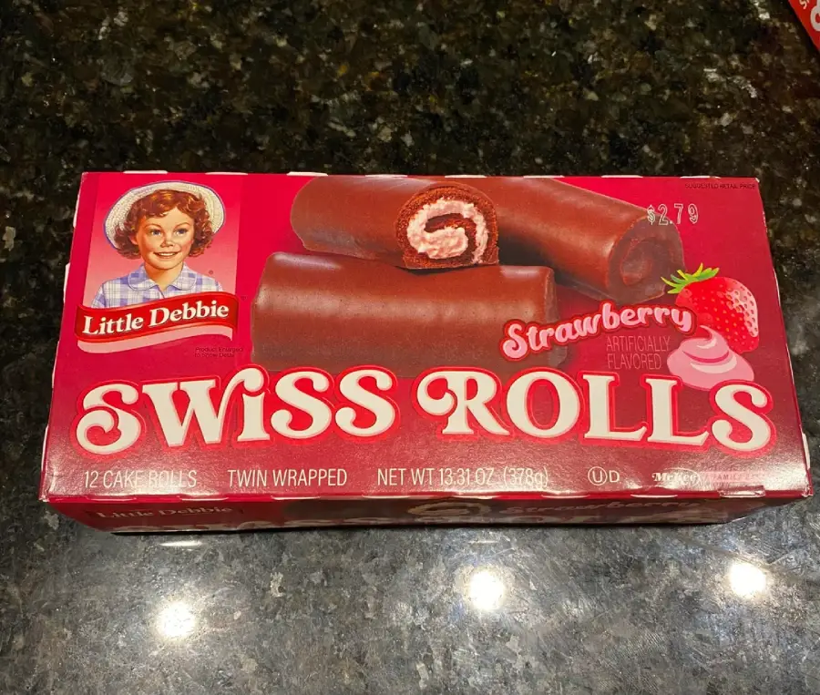 A red box of Little Debbie Strawberry Swiss Rolls featuring an illustration of a woman, images of chocolate-covered cake rolls with strawberry filling, and a strawberry on the front.