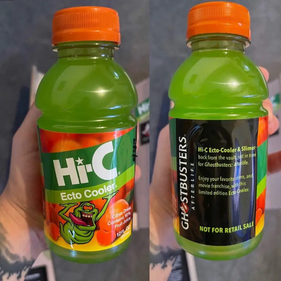 A hand holds a small bottle of Hi-C Ecto Cooler with green juice, featuring Slimer from Ghostbusters on the front and a black label on the back explaining it’s a limited edition not for retail sale.