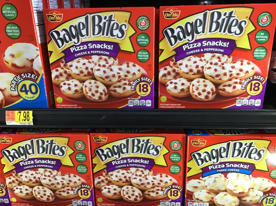Five boxes of Bagel Bites Pizza Snacks (Cheese & Pepperoni) on a store shelf, each box containing 18 mini bagels topped with cheese and pepperoni. Price tag below shows $7.98.