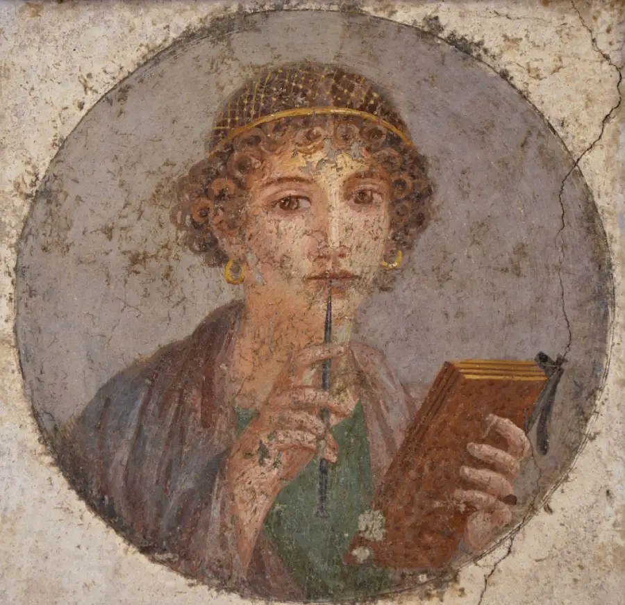 Ancient fresco of a woman with curly hair holding a stylus to her lips and a wooden tablet in her hand, set inside a circular frame with a worn, textured background.