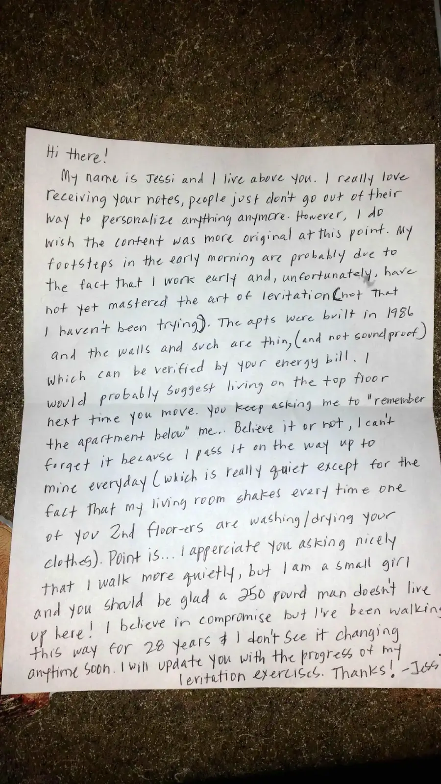 A handwritten letter on lined paper is illuminated by a flashlight, resting on the ground with dirt and dried grass visible around the edges. The letter discusses the writer’s name, life, and thoughts on writing letters.