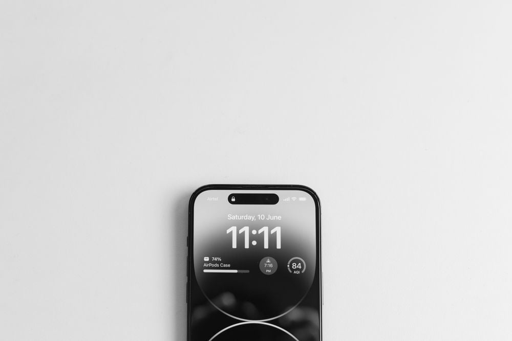 A smartphone displaying the lock screen with the time 11:11 and the date Saturday, 10 June, is placed on a white surface, with only the top portion of the phone visible.