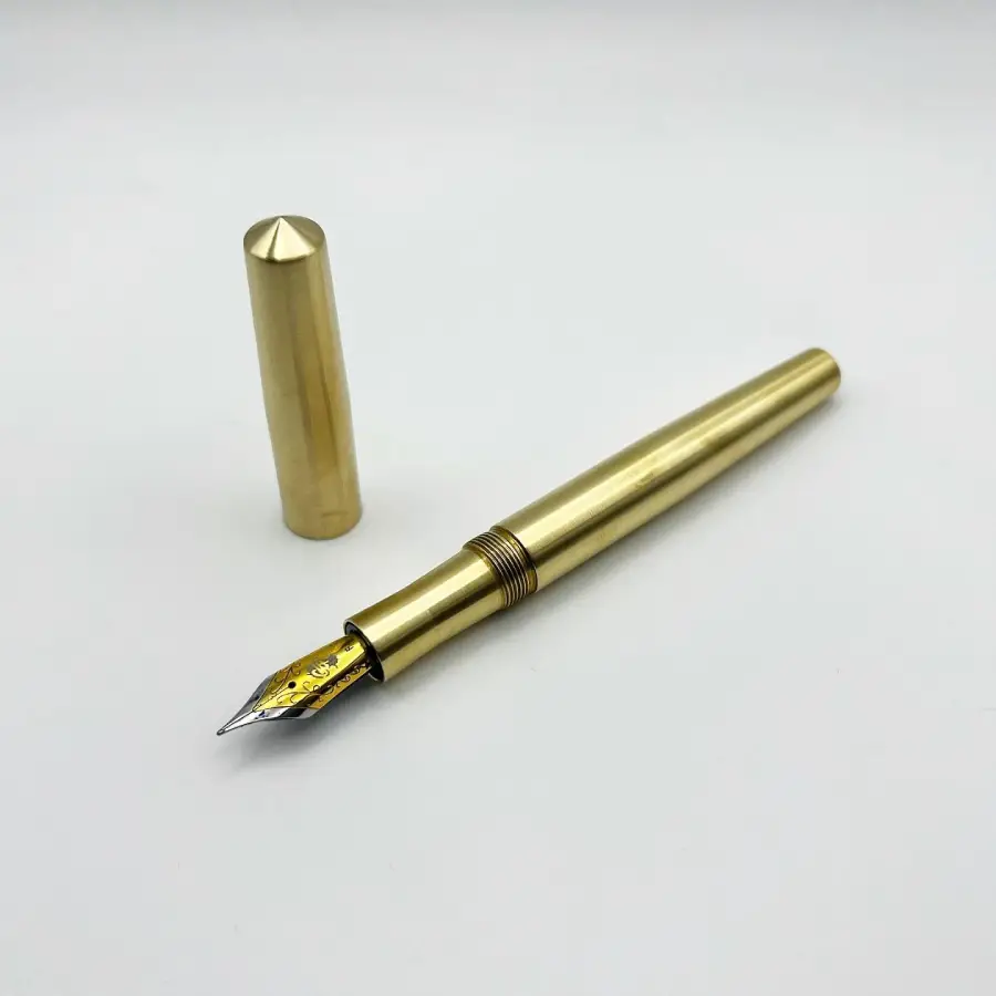 A gold-colored fountain pen with its cap removed and placed nearby, displayed on a plain white background.