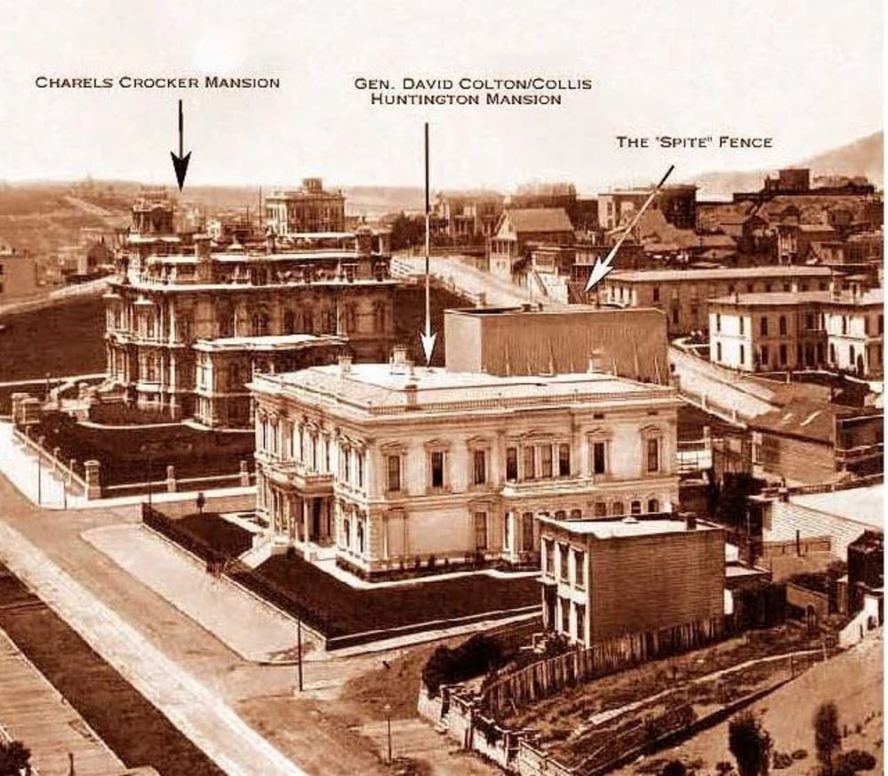 Sepia photo of a city block showing two large mansions, labeled as Charles Crocker Mansion and Colton/Huntington Mansion, with a tall wooden fence labeled “The ‘Spite’ Fence” between them.
