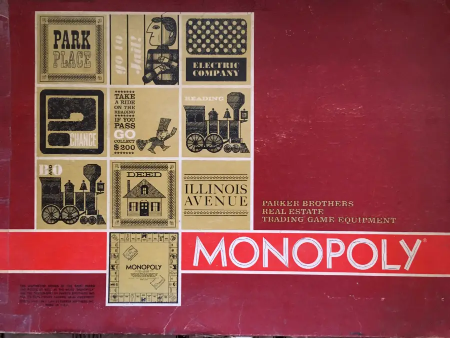 Vintage Monopoly board game box with a red background, featuring images of game cards like Park Place, Electric Company, Illinois Avenue, and train illustrations. “MONOPOLY” is written in large white letters at the bottom right.