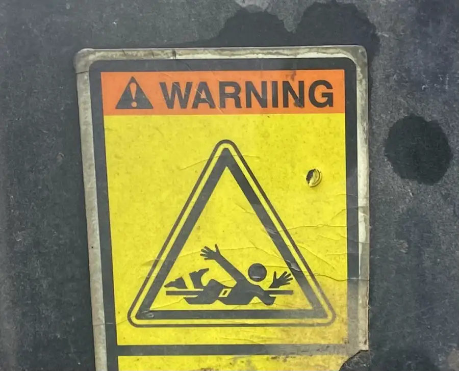 Yellow warning sign with a stick figure slipping and falling backward, arms raised, inside a triangular caution symbol, indicating a potential fall hazard.