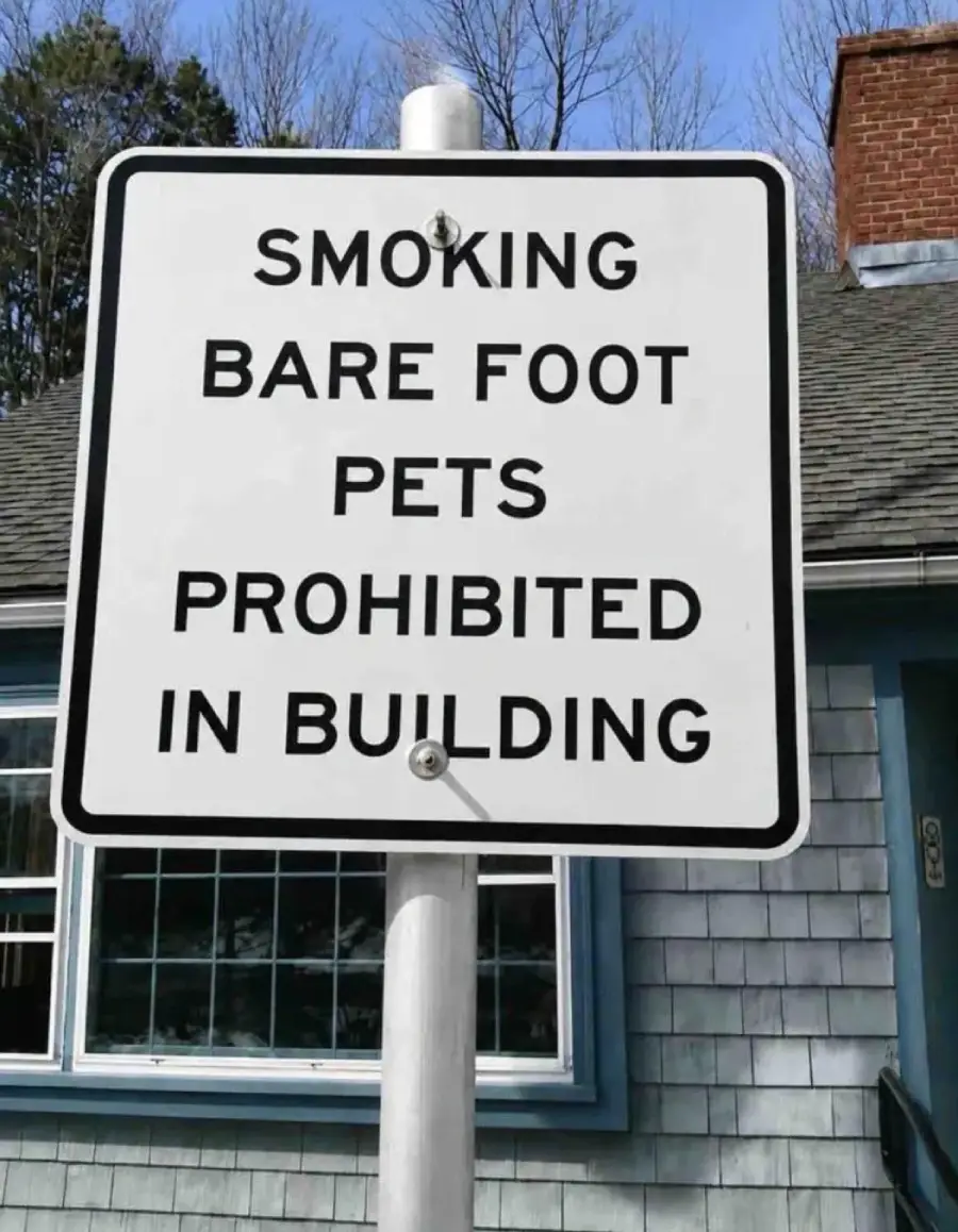 A sign reads: “SMOKING BARE FOOT PETS PROHIBITED IN BUILDING,” with unclear formatting making the message confusing.