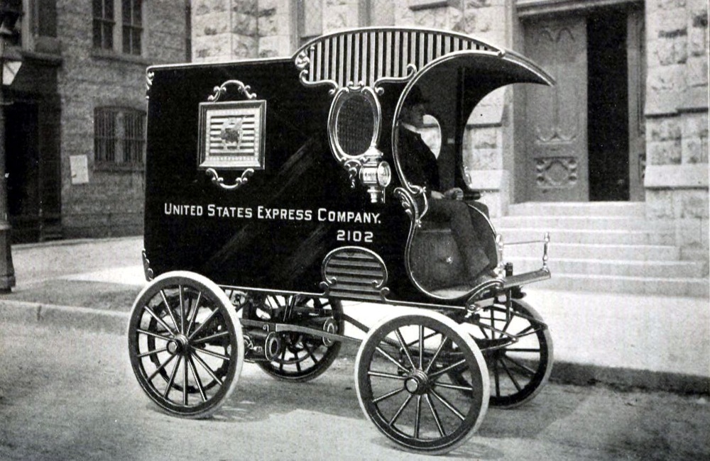 A driver seated in an early electric delivery automobile from 1900.