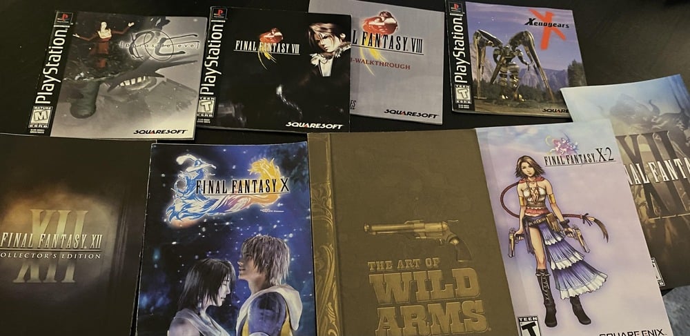 Several PlayStation video game cases and booklets are spread out, featuring titles like Final Fantasy VII, Final Fantasy X, Xenogears, Wild Arms, and their respective artwork and logos.