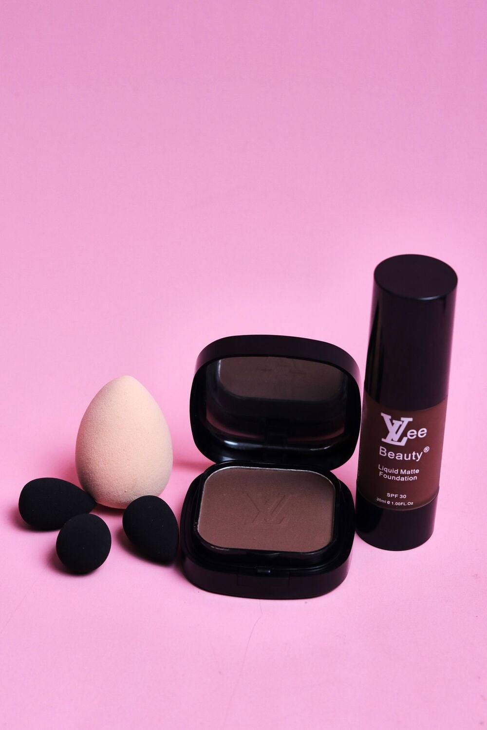 Yzee Beauty liquid matte foundation, a compact powder with a mirror, and four makeup sponges.