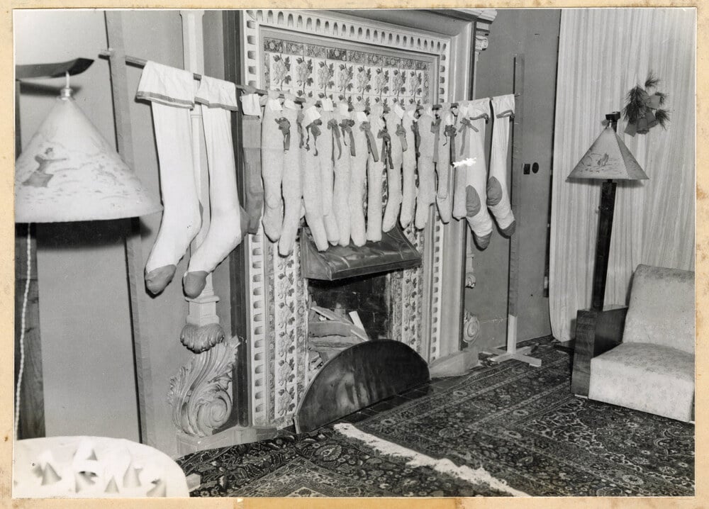 A long row of stockings hung from a rod in front of a decorative fireplace.