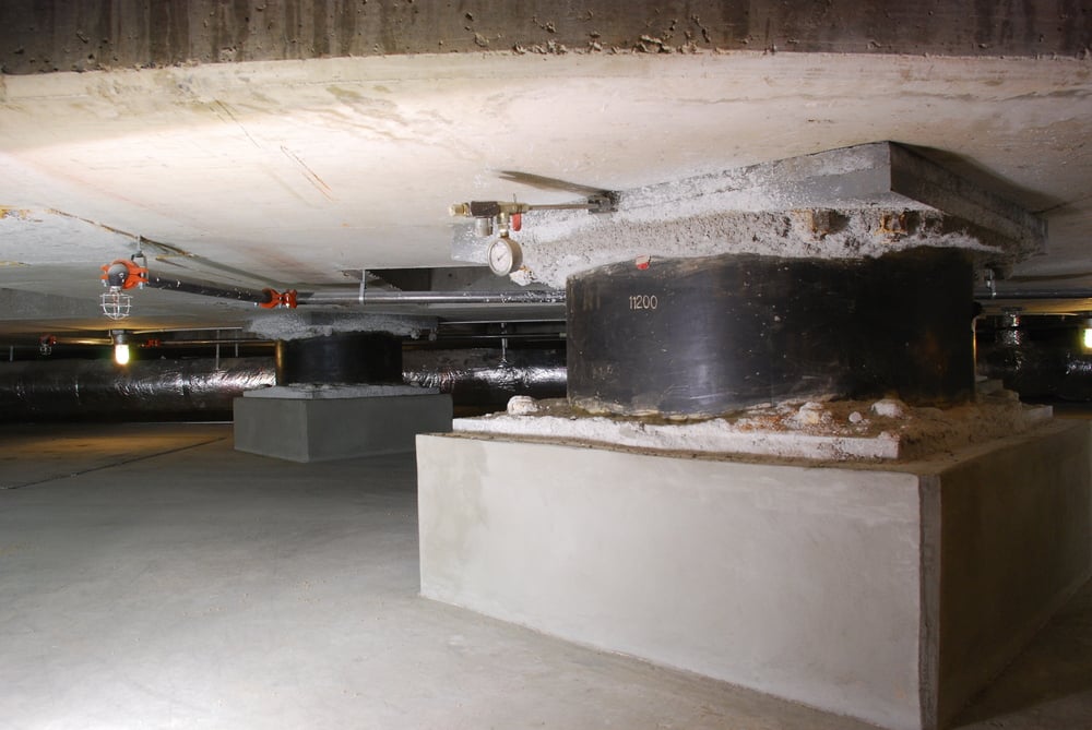 Large circular base isolators supporting a concrete building foundation.