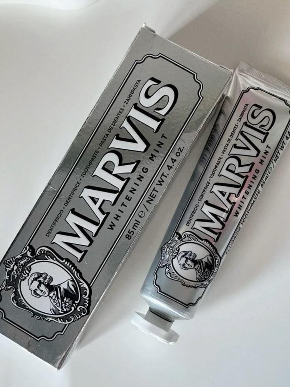 A box and a tube of Marvis Whitening Mint toothpaste, both with silver packaging and a vintage-style portrait logo.