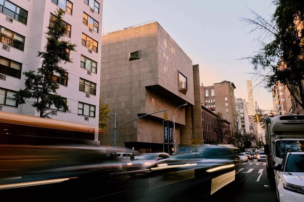 The Whitney Museum of American Art building on a city street with motion-blurred traffic in the foreground.