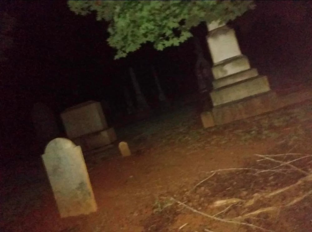 Several stone grave markers in a cemetery at night.