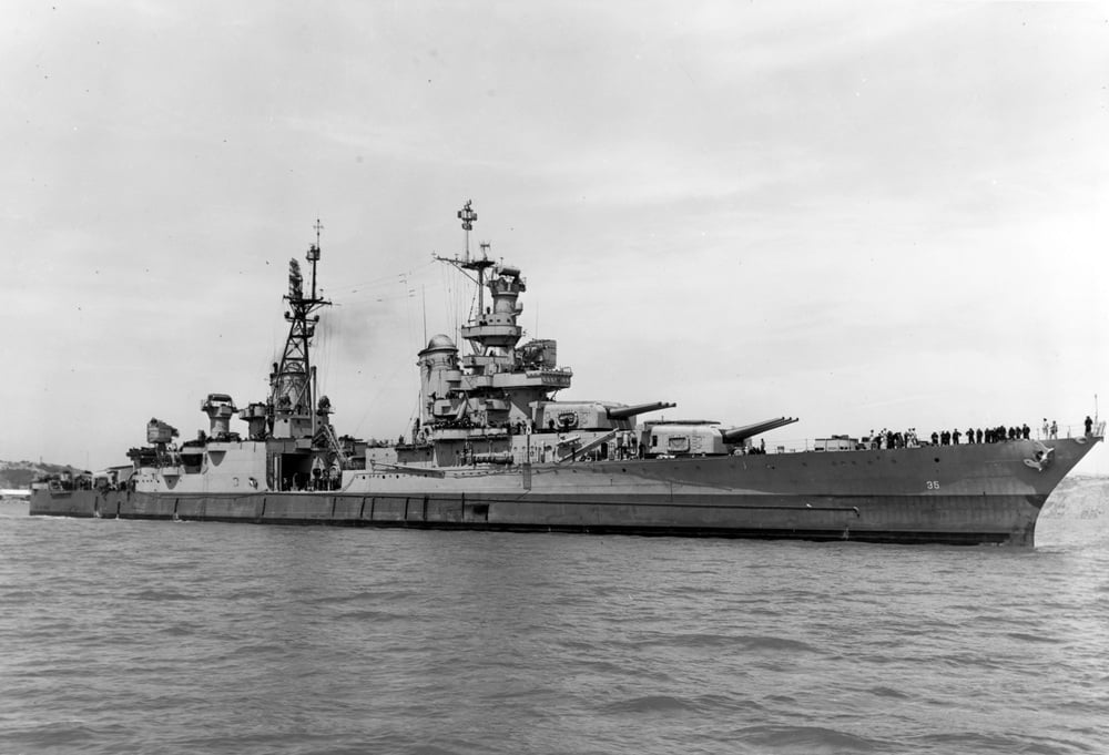 A black-and-white profile view of the USS Indianapolis cruising through the water.