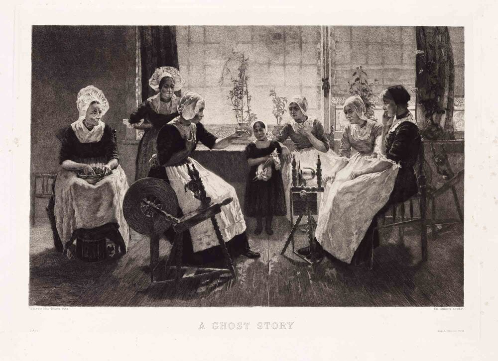 Six women and a child in traditional clothing sit and stand in a room, with one woman gesturing as she speaks to the others.