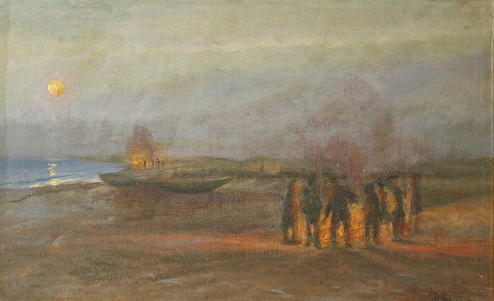 A group of people stand around a bonfire on a beach at dusk under a full moon.