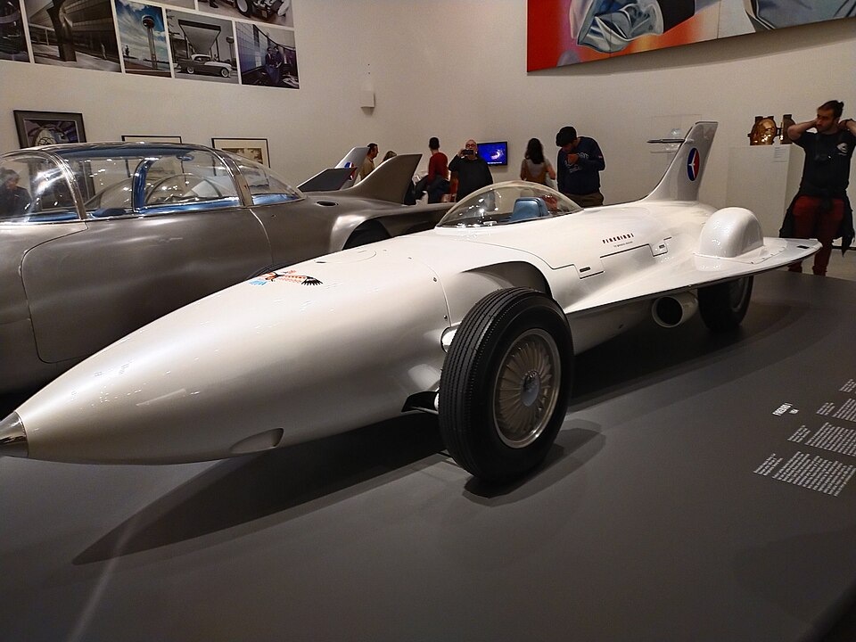 A white General Motors Firebird I concept car on display in a museum.
