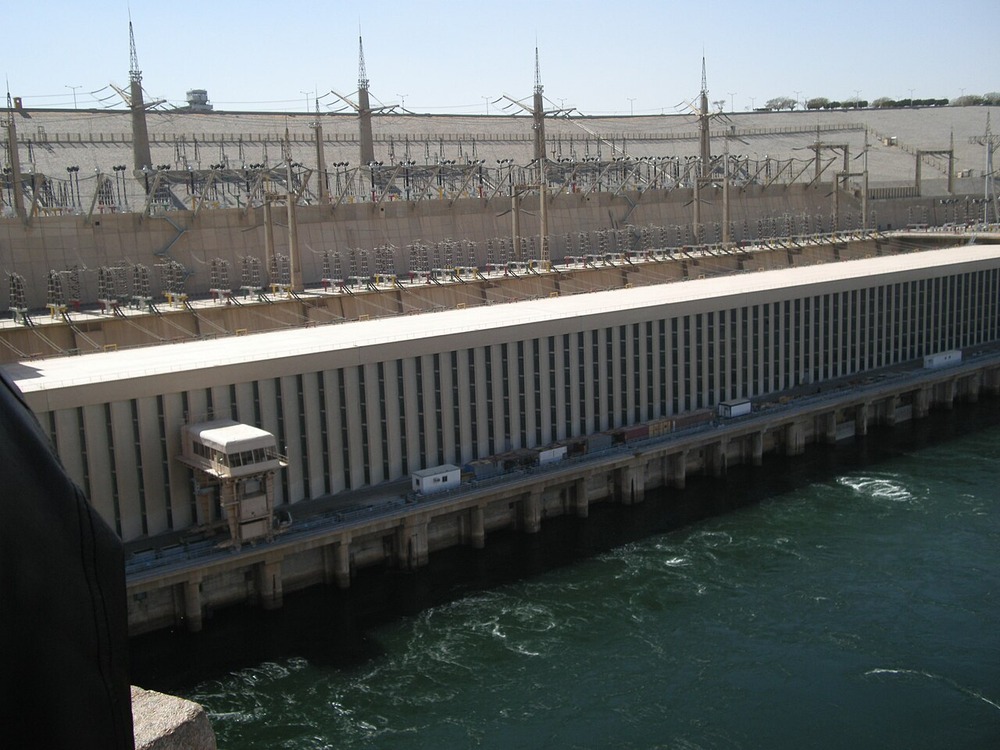 The Aswan High Dam with its concrete spillway structure, power station equipment, and water flowing through the base.
