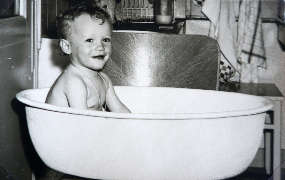 A young child smiling while sitting in a round basin bathtub.