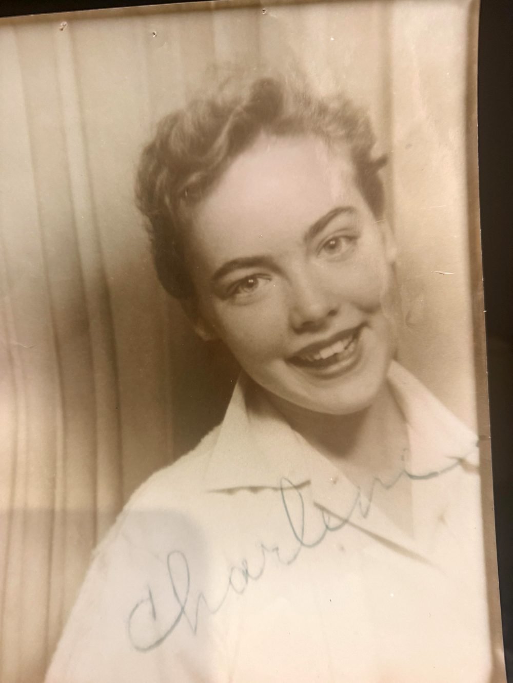 Sepia-toned portrait of a smiling young woman with short hair, featuring the handwritten name “Charlene” across the bottom.