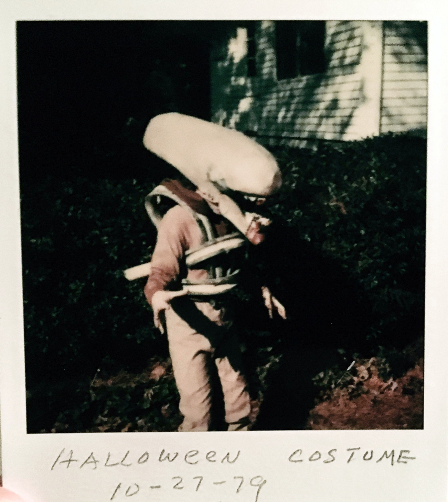 A person in a homemade alien costume poses outside on grass. The photo has “HALLOWEEN COSTUME 10-27-79” handwritten at the bottom.