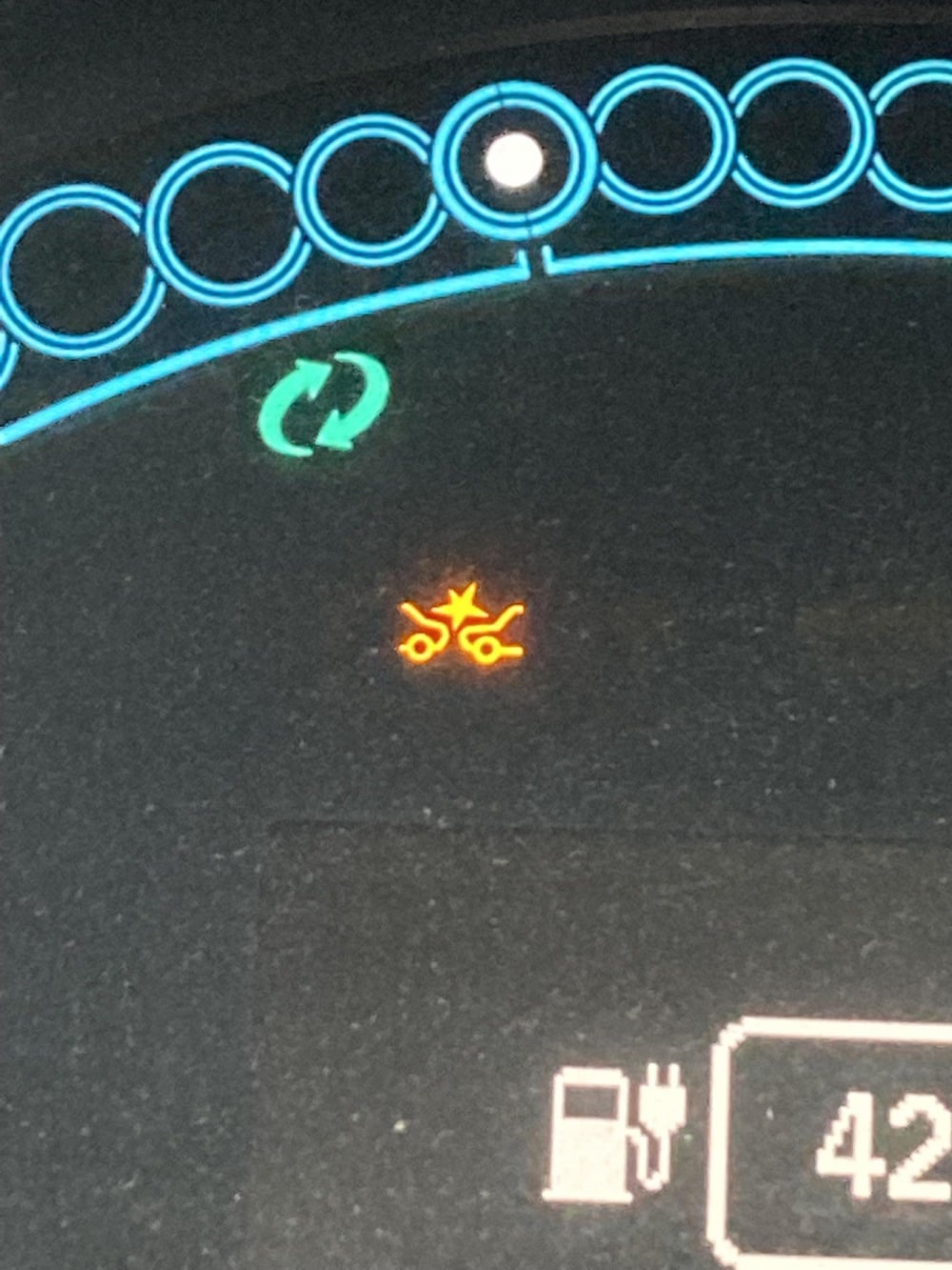 Dashboard display showing a green recycling icon and an amber warning light depicting two symbols with a star between them, above a fuel pump icon.
