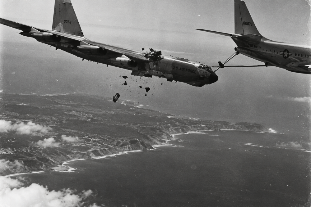 A B-52 bomber colliding with a KC-135 tanker mid-air, with debris falling toward the coastline below.