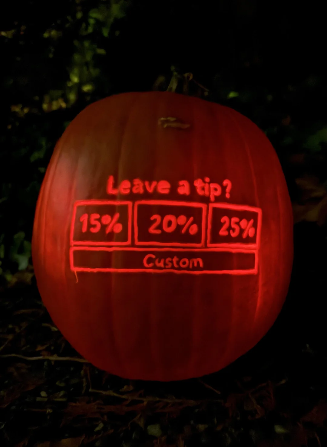 A glowing carved pumpkin featuring a digital tip screen with the options 15%, 20%, 25%, and custom.