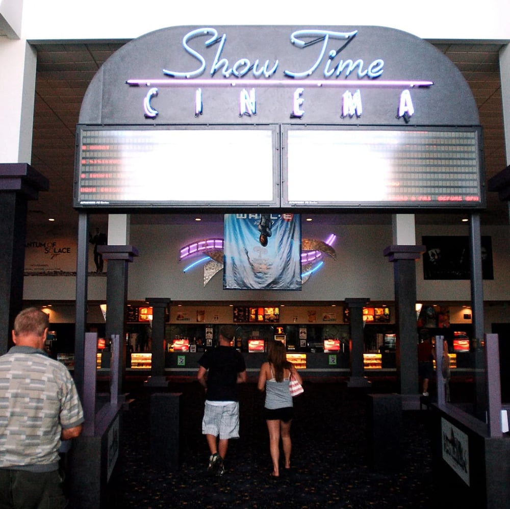 The entrance to Show Time Cinema with two people walking toward the ticket counter.