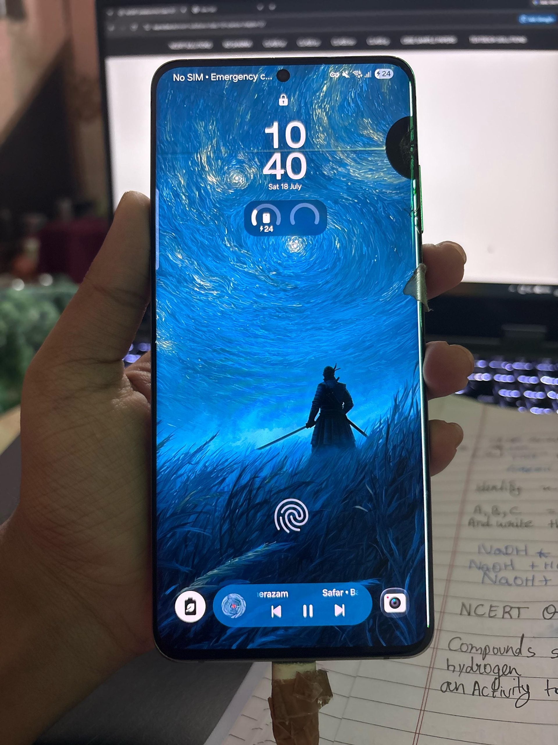 A hand holds a smartphone displaying a lock screen with a wallpaper of a samurai standing in a field under a swirling blue sky, with a music player widget and fingerprint icon at the bottom.