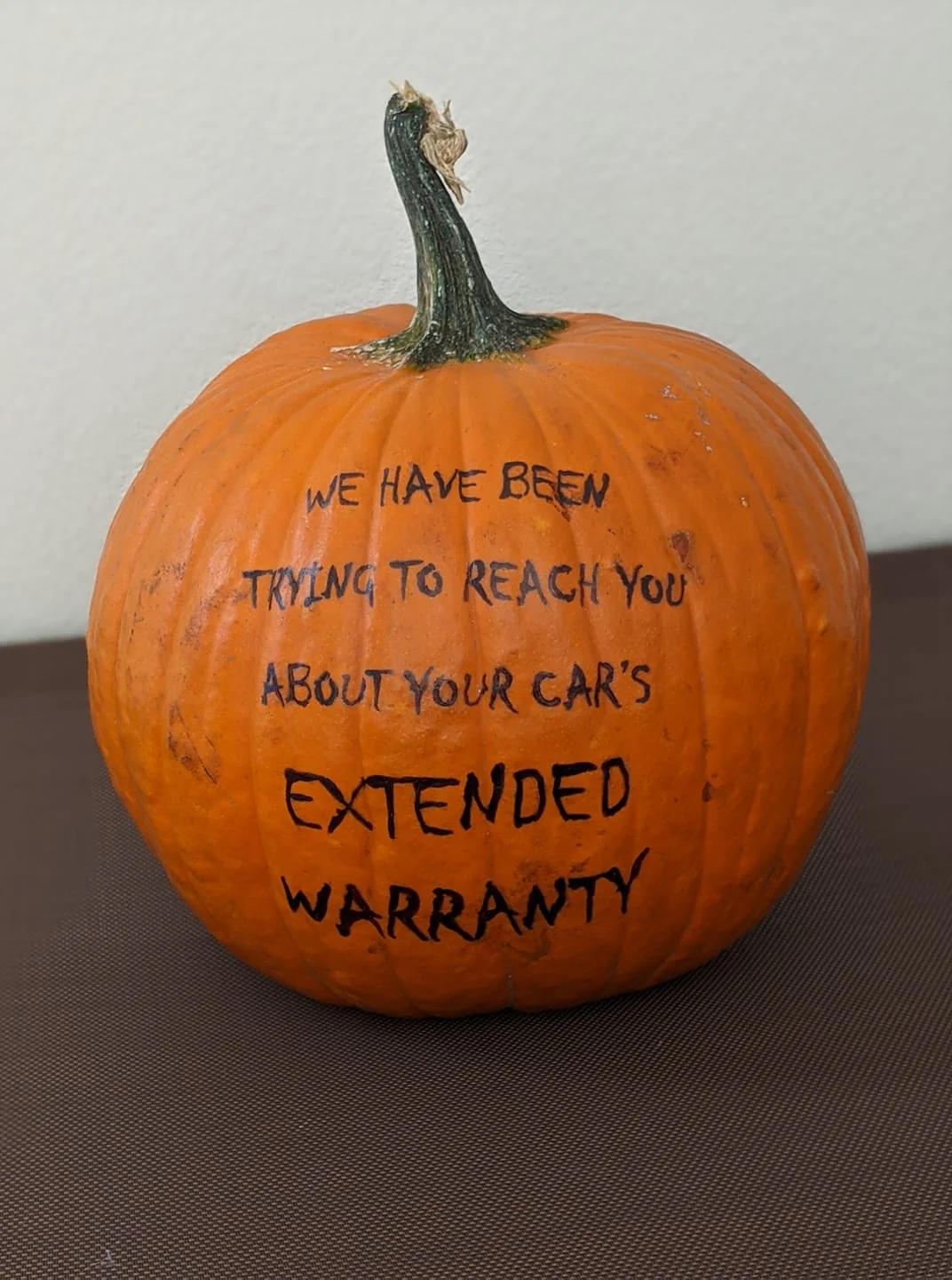 An orange pumpkin with the handwritten text, “We have been trying to reach you about your car’s extended warranty.”