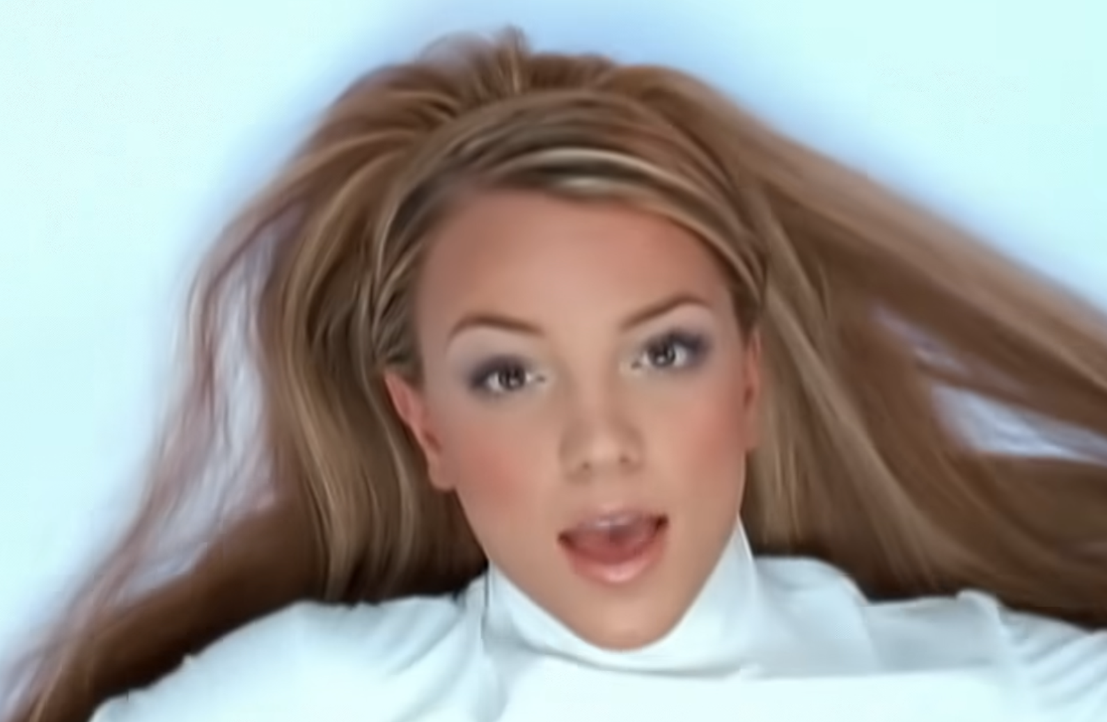 Britney Spears wearing a white turtleneck with her hair spread out behind her.
