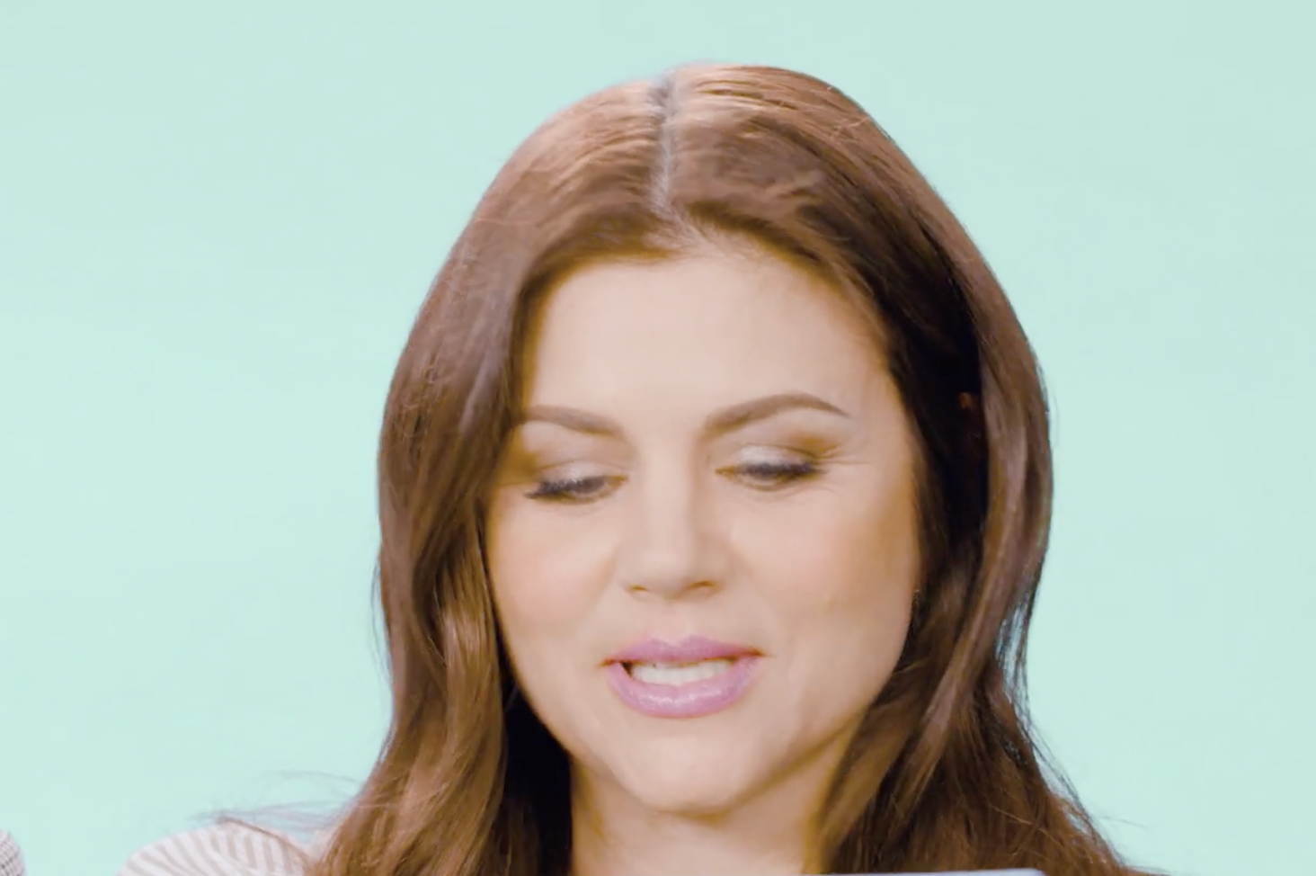 A woman with brown hair looking downward while speaking.