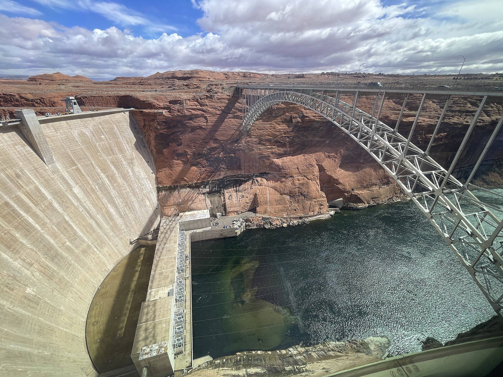 Glen Canyon Dam and the arched bridge spanning the river between red rock canyon walls.