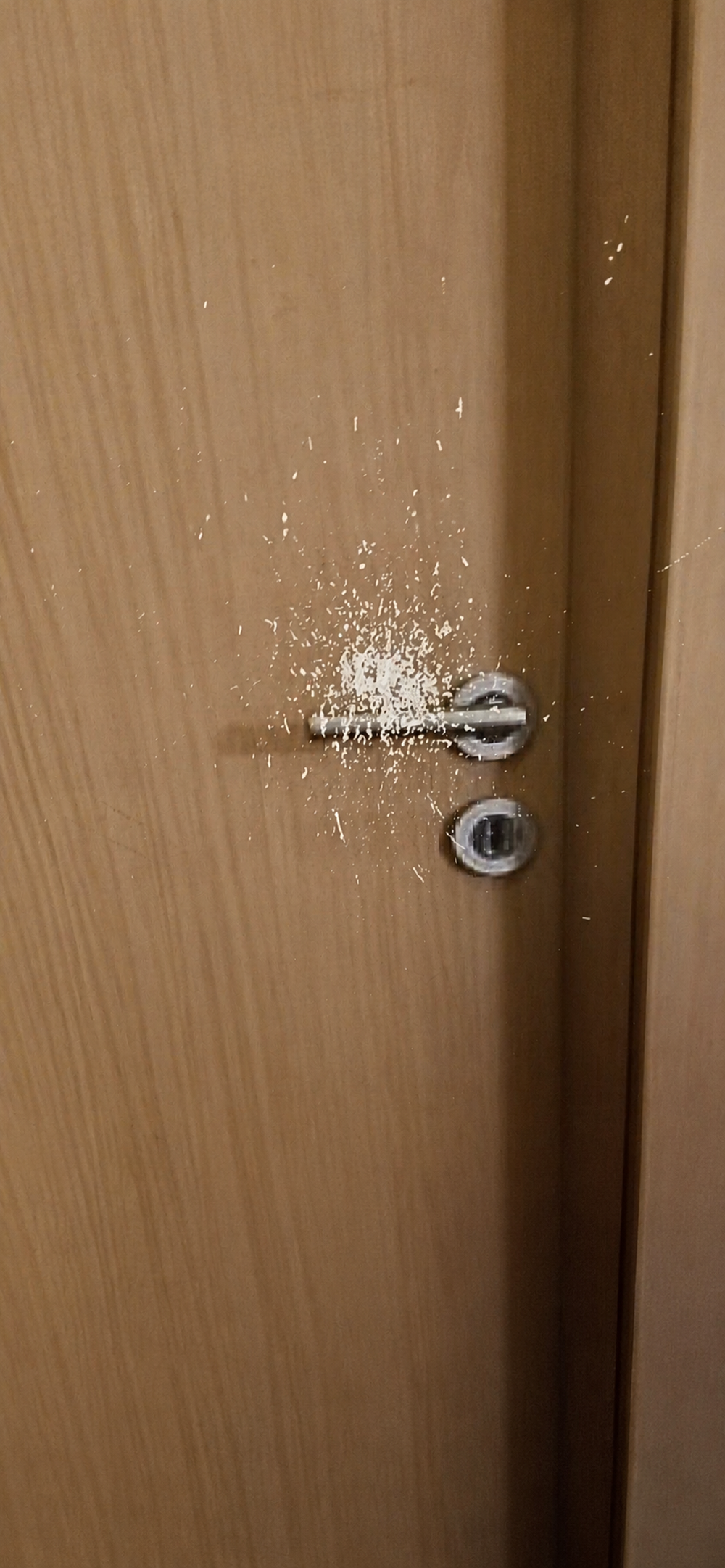 A wooden door with its finish worn away around the handle and lock.