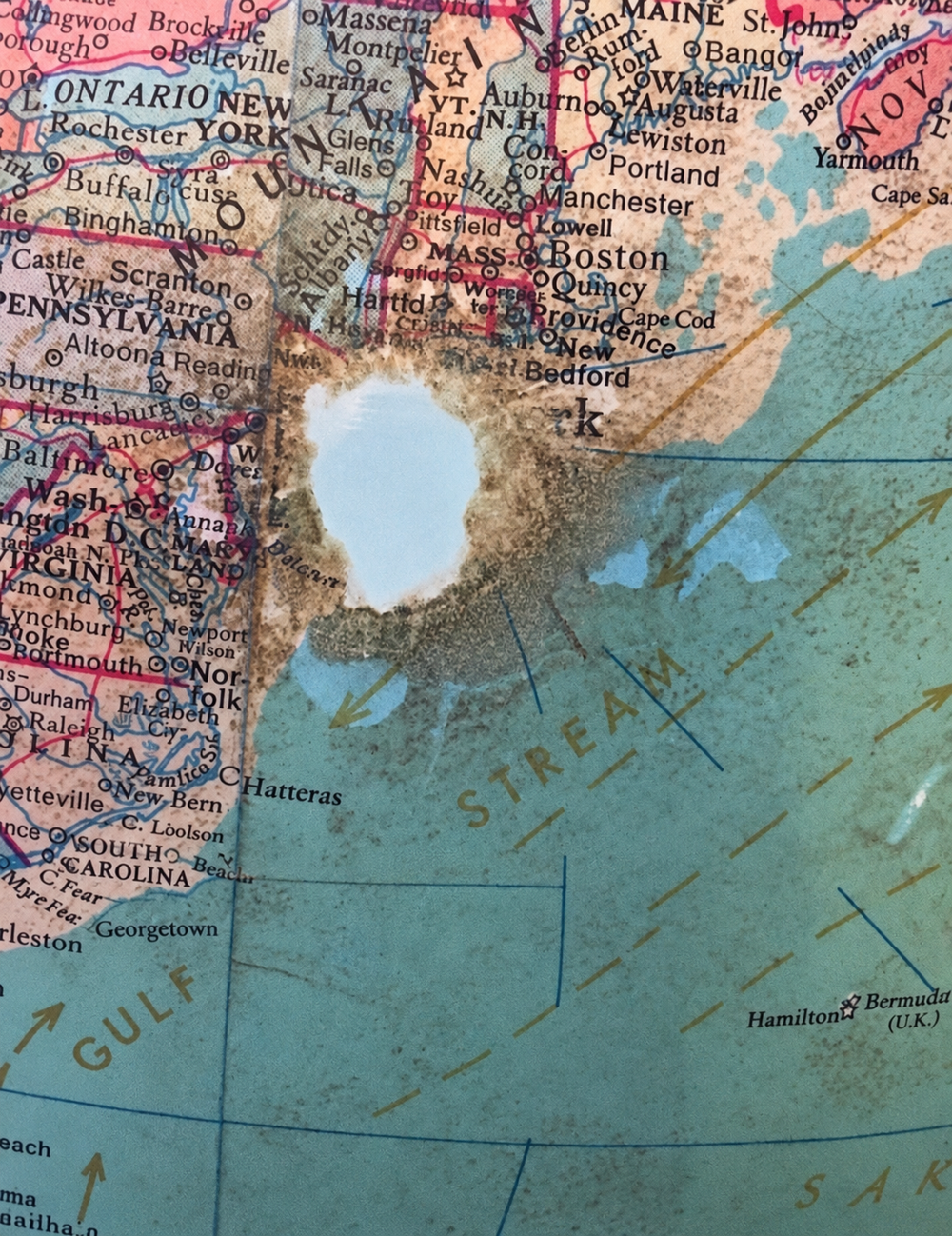 A worn map with a conspicuous hole through the northeastern United States.