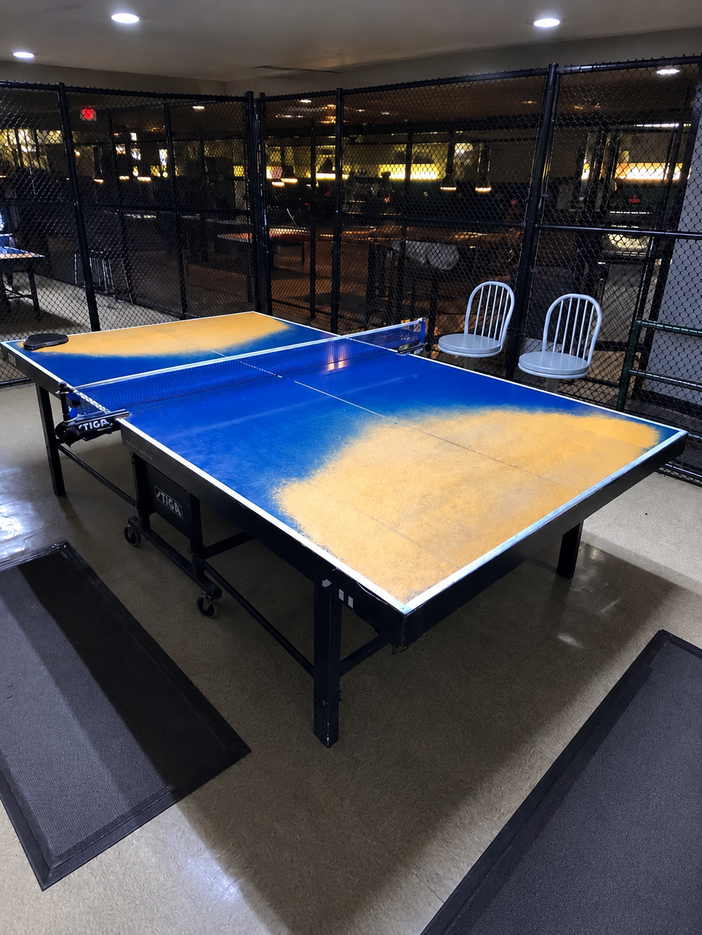 A ping-pong table with large worn patches across its playing surface.