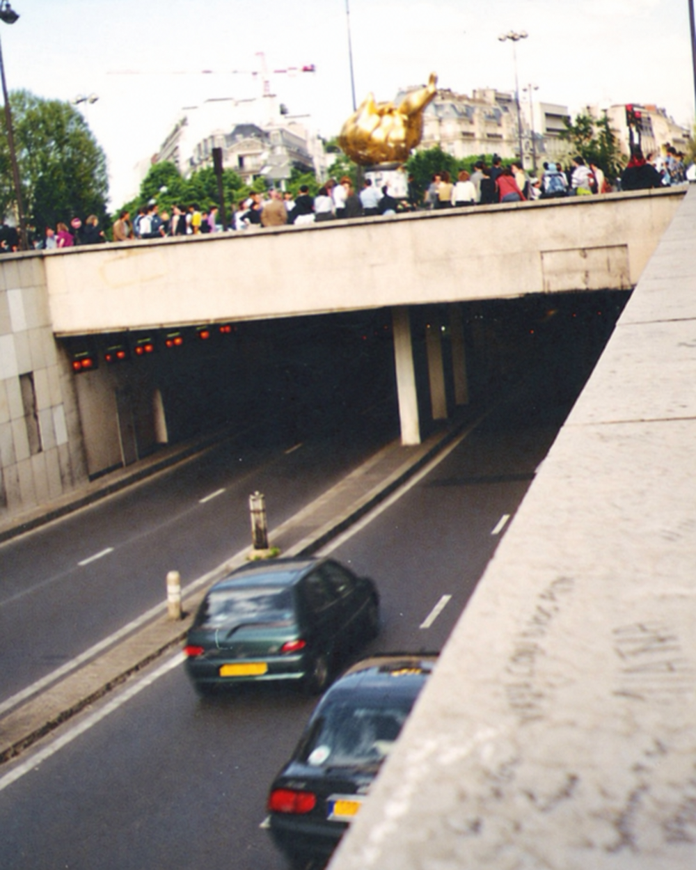 Cars driving through the underpass beneath the Flame of Liberty sculpture in Paris.