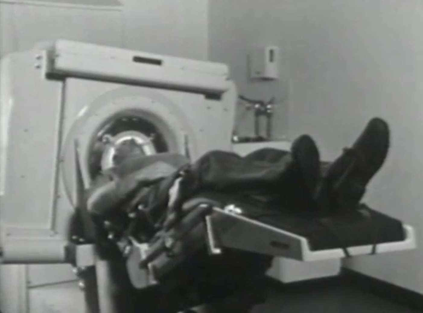 A person lying on a medical scanning table being positioned into a CT or MRI machine.