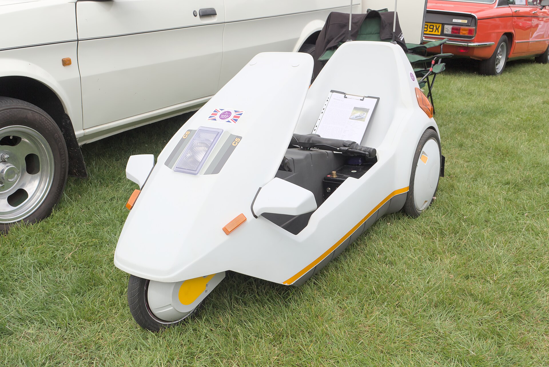A white Sinclair C5 electric tricycle parked on a grass field.