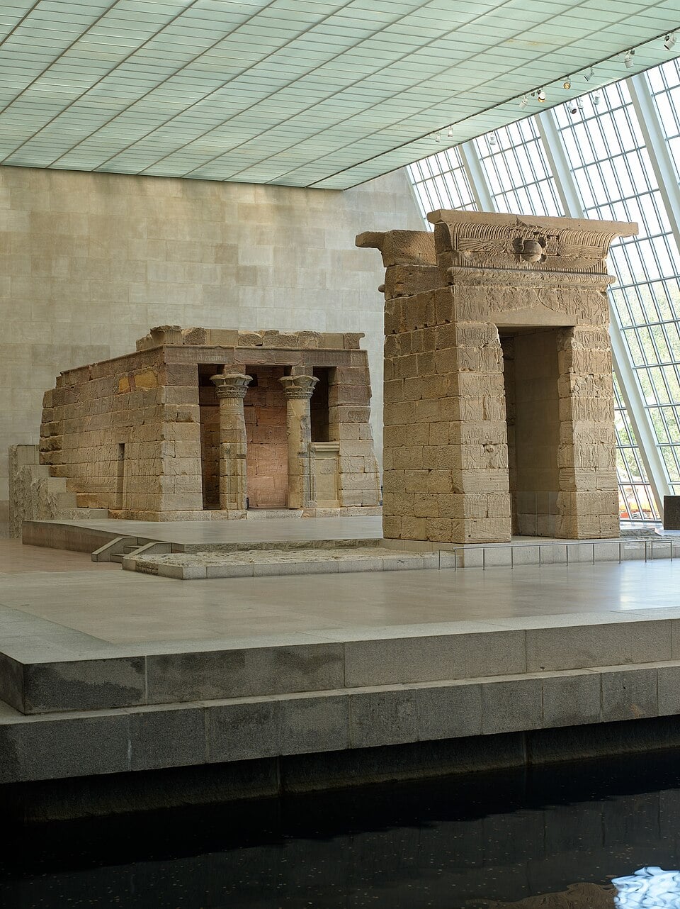 The Temple of Dendur displayed inside a large, glass-walled museum gallery.