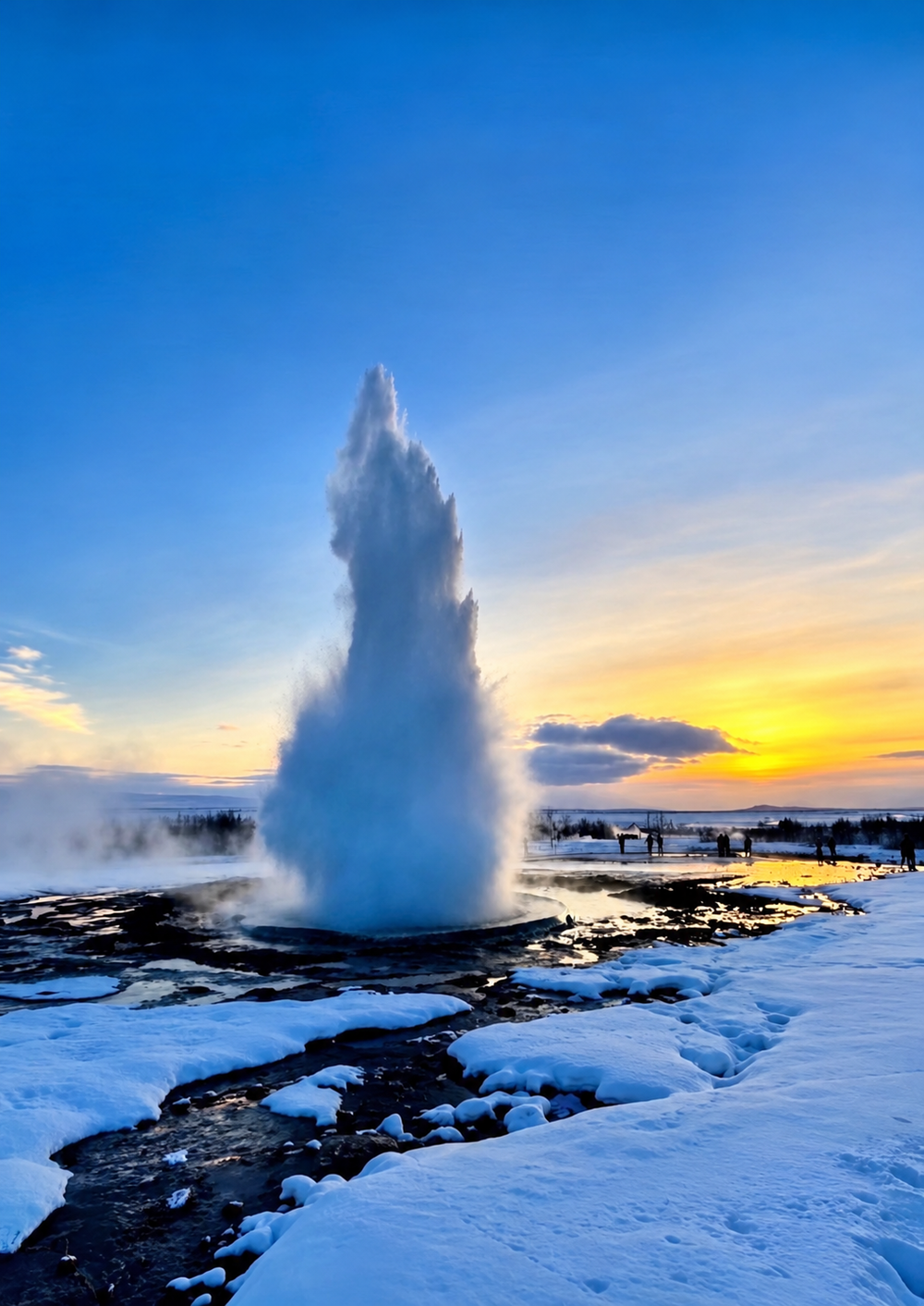 A geyser erupts into the air over a snowy landscape at sunset.