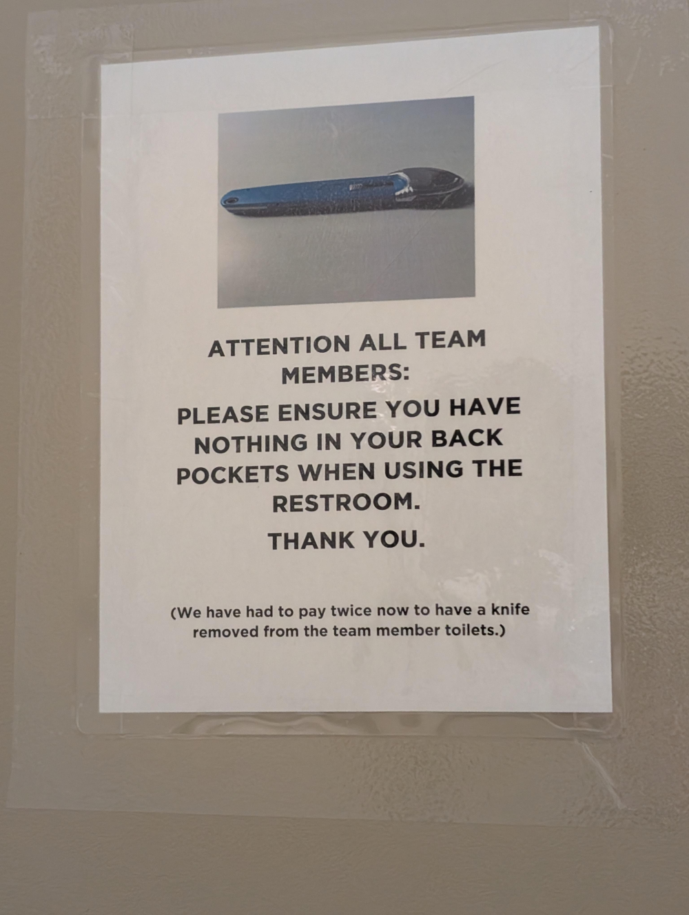 Sign instructing team members to empty back pockets before using the restroom to prevent knives from falling into toilets.